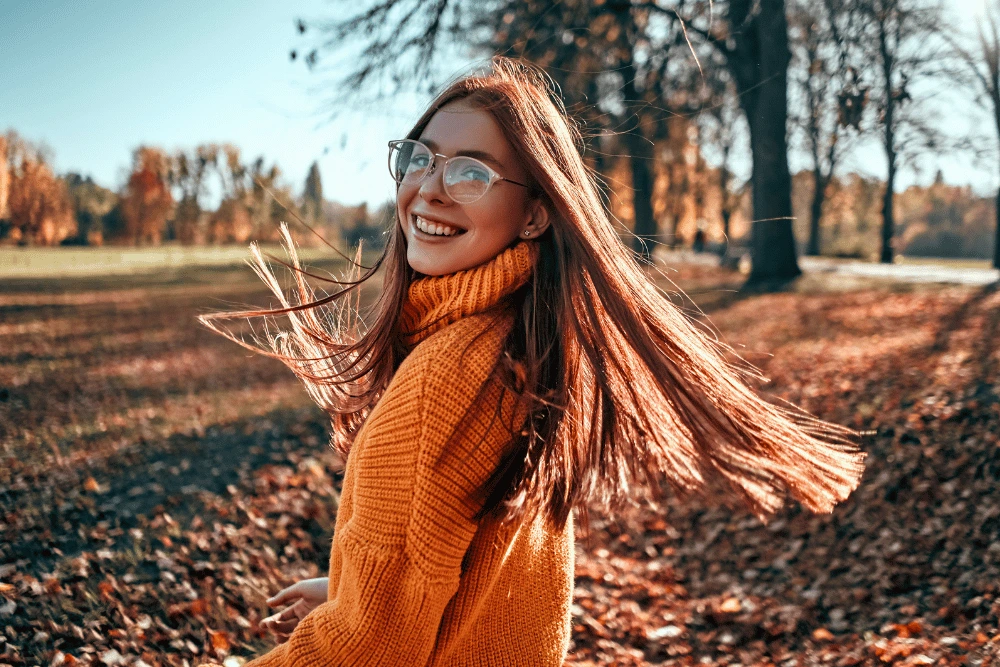 a woman smiling and standing outdoors in fall
