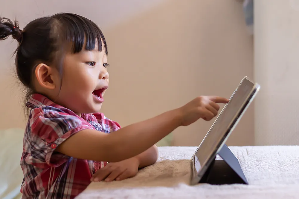 a little girl playing on a tablet at home
